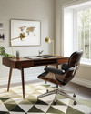 A Mid-Century Modern home office featuring a sleek walnut desk, an Eames Aluminum Group chair in black leather, a geometric area rug with olive green accents, and a brass desk lamp. — view 4
