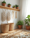 A bright boho mudroom featuring a wooden peg rail with woven baskets and macrame wall hangings, a layered jute and patterned rug, and potted green plants in terracotta pots, all bathed in natural light.