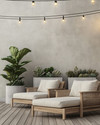 A minimalist boho deck featuring light teak wood lounge chairs with off-white cushions, subtle woven rattan accents, and large concrete planters holding a Fiddle-Leaf Fig and various succulents, all under warm string lights. — styling and décor detail