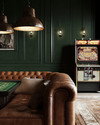 Rustic game room showcasing a blend of vintage and modern elements, with deep forest green walls, a classic leather chesterfield sofa, a vintage arcade machine, and industrial pendant lights illuminating a sleek poker table. — close-up of textures and materials