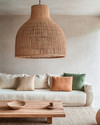 A boho poolhouse interior with a large woven rattan pendant light, a cream sofa with textured cushions, and a natural wood coffee table. Soft, diffused lighting creates a serene atmosphere, complemented by muted terracotta and sage green accents. — close-up of textures and materials