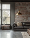 An industrial living room with a cohesive color story featuring a charcoal leather sofa, exposed brick wall, and a large metal-framed window. Warm grey walls, a polished concrete floor, and an aged brass pendant light add to the calm, urban aesthetic. — close-up of textures and materials