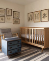 A modern baby and kids room featuring a natural maple crib, a mid-century modern rocking chair with grey linen upholstery, and a vintage wooden toy chest in faded blue. The walls are painted in a warm off-white, complemented by a subtle striped rug and a collection of vintage framed botanical prints. — close-up of textures and materials