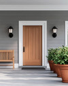 A serene Scandinavian exterior with a light gray facade, crisp white trim, and a natural wood front door. Simple black sconces flank the door, and a minimalist wooden bench sits beside terracotta planters filled with green foliage, all under a bright, clear sky.