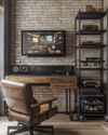 A compact industrial game room featuring a wall-mounted wooden desk with a large monitor, exposed brick wallpaper, and black metal shelving holding retro consoles. A distressed leather gaming chair sits in front, with a small industrial-style bar cart to the side. — styling and décor detail