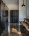 Minimalist industrial mudroom with matte black steel lockers, a polished concrete floor, and a reclaimed oak bench, illuminated by natural light. — styling and décor detail