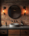 Industrial powder room featuring a wall of exposed red brick, a reclaimed wood vanity with a concrete sink basin, and a round black metal mirror. Dark iron sconces with exposed Edison bulbs illuminate the space, and a patinated brass faucet adds warmth. — close-up of textures and materials