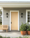 A serene Scandinavian exterior with a light gray facade, crisp white trim, and a natural wood front door. Simple black sconces flank the door, and a minimalist wooden bench sits beside terracotta planters filled with green foliage, all under a bright, clear sky. — close-up of textures and materials