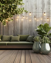 A budget-friendly Mid-Century Modern deck featuring stained pine decking, a low-slung sofa with olive green cushions, and a kidney-shaped side table. Fiberglass planters hold architectural succulents and a large fiddle-leaf fig, all under string lights with exposed bulbs. — close-up of textures and materials