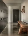 Minimalist industrial mudroom with matte black steel lockers, a polished concrete floor, and a reclaimed oak bench, illuminated by natural light.