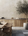 Japandi outdoor kitchen featuring untreated teak cabinetry, honed concrete countertops, and bluestone pavers. Minimalist rattan dining chairs surround a solid wood table, with an olive tree in an unglazed ceramic planter providing a natural accent. — styling and décor detail