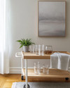 A serene Scandinavian home bar setup in a rental apartment featuring a light wood bar cart with white metal accents, minimalist glassware, and a small potted fern. Soft grey wall art and a textured linen tea towel complete the inviting, renter-friendly space. — styling and décor detail