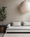 A serene Japandi poolhouse interior featuring a low-slung white oak daybed with natural linen cushions, a dark wenge wood side table, and a large, round paper lantern pendant light. The walls are a soft greige, complemented by a subtle textured rug in cream and a tall, slender fiddle leaf fig plant in a terracotta pot. — styling and décor detail