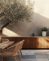Japandi outdoor kitchen featuring untreated teak cabinetry, honed concrete countertops, and bluestone pavers. Minimalist rattan dining chairs surround a solid wood table, with an olive tree in an unglazed ceramic planter providing a natural accent. — close-up of textures and materials