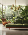 A Mid-Century Modern living room showcasing a low-slung olive green sofa with a walnut frame, an Eames Lounge Chair, and a brass Sputnik chandelier, all overlooking a lush garden through large windows. — styling and décor detail