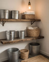 Rustic laundry room with a reclaimed wood floating shelf, galvanized metal buckets, woven rattan baskets, and a small braided jute rug on the floor, lit by a warm Edison bulb pendant. — close-up of textures and materials