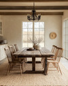 A rustic dining room featuring a large, solid reclaimed oak dining table, mismatched wooden chairs, and a natural jute area rug, illuminated by a wrought iron chandelier, with walls painted in a warm antique white. — close-up of textures and materials
