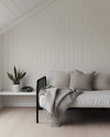 A bright Scandinavian garage loft with white walls, pale oak flooring, and a minimalist black metal frame daybed, accented with a light grey throw and a simple potted snake plant on a white floating shelf. — close-up of textures and materials