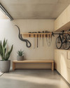 A small Japandi garage featuring light birch plywood cabinetry, a polished concrete floor, and walls painted in a soft off-white. A minimalist bamboo storage bench sits against one wall, with a single snake plant in a grey ceramic pot. Wall-mounted racks hold neatly organized tools, and a bicycle is suspended, maximizing floor space. — alternate angle