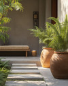 A serene Japandi-style driveway featuring large unglazed terracotta planters with lush green ferns, smooth concrete stepping stones, and subtle solar-powered pathway lights casting a warm glow. A simple wooden bench with a woven cushion sits near the entrance, embodying natural textures and minimalist design. — alternate angle