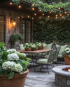 A cozy traditional patio featuring a wrought iron dining set with sage green cushions, a wooden dining table, and warm string lights draped overhead. Terracotta pots filled with lush greenery and blooming hydrangeas are placed around a stone fire pit. — close-up of textures and materials