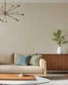A Mid-Century Modern great room featuring a low-slung sofa in warm beige, a walnut credenza, and a Noguchi coffee table. Accents of sage green and a muted sky blue are visible in throw pillows and a ceramic vase, with a Sputnik chandelier overhead and a Fiddle Leaf Fig in a white planter. — styling and décor detail