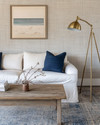 Coastal Landscape living room blending vintage and modern elements, featuring a reclaimed teak coffee table, a linen slipcover sofa, and a brushed brass floor lamp, with walls painted in a soft Balboa Mist grey and accents of deep ocean blue and coral. — styling and décor detail