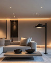 A modern living room at dusk with layered lighting, featuring recessed ceiling lights, a sleek matte black floor lamp beside a light gray sofa, and a sculptural pendant light illuminating a minimalist coffee table. Warm white light creates an inviting ambiance. — close-up of textures and materials