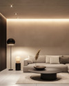 A modern living room at dusk with layered lighting, featuring recessed ceiling lights, a sleek matte black floor lamp beside a light gray sofa, and a sculptural pendant light illuminating a minimalist coffee table. Warm white light creates an inviting ambiance. — alternate angle