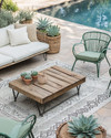 A boho poolside area featuring a mix of vintage wrought-iron chairs in sage green and a modern low-slung outdoor sofa with natural linen cushions. A reclaimed wooden coffee table sits on a layered outdoor rug with geometric patterns, surrounded by potted succulents and woven rattan accents. — alternate angle