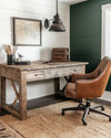 A cozy rustic home office featuring a reclaimed oak desk, a distressed cognac leather chair, and a jute rug. Walls are painted a warm off-white, complemented by a deep forest green accent wall, with an iron pendant light illuminating the space. — close-up of textures and materials