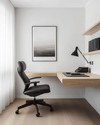 Modern home office with a minimalist aesthetic featuring a light oak floating desk, a black ergonomic chair, white walls, and a sleek matte black desk lamp. — close-up of textures and materials