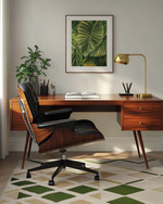 A Mid-Century Modern home office featuring a sleek walnut desk, an Eames Aluminum Group chair in black leather, a geometric area rug with olive green accents, and a brass desk lamp. — view 3