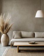 A minimalist Japandi living room featuring a low-profile sofa in natural linen, a light ash wood coffee table, and a large, unglazed ceramic vase with dried pampas grass. The walls are painted in a warm grey, complemented by soft, diffused light from a paper-shade floor lamp. — view 4