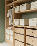 A Japandi-style closet featuring light ash wood shelving and drawers, cream linen storage boxes, and a subtle sage green accent wall, bathed in soft, natural light. — view 4
