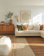 A bohemian great room blending vintage and modern elements, featuring a cream sectional sofa, a mid-century teak credenza, layered jute and sheepskin rugs, and a mix of terracotta and sage green accents. — view 4