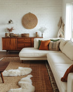 A bohemian great room blending vintage and modern elements, featuring a cream sectional sofa, a mid-century teak credenza, layered jute and sheepskin rugs, and a mix of terracotta and sage green accents. — view 2