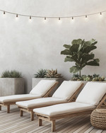A minimalist boho deck featuring light teak wood lounge chairs with off-white cushions, subtle woven rattan accents, and large concrete planters holding a Fiddle-Leaf Fig and various succulents, all under warm string lights. — close-up of textures and materials