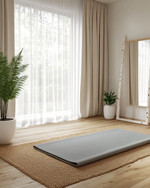 A Scandinavian home gym designed for a seasonal refresh, featuring light wood flooring, white walls, and a large window with sheer curtains. A natural jute rug is placed under a light grey yoga mat, with a potted fern in a white ceramic planter and a simple birch-framed mirror nearby. — styling and décor detail