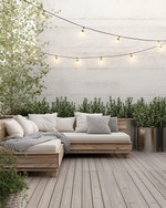 A serene Scandinavian deck with light-toned wooden flooring, a low-profile wooden lounge set with off-white cushions and a chunky knit grey wool throw, minimalist galvanized steel planters with evergreens, and soft string lights overhead.