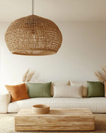 A boho poolhouse interior with a large woven rattan pendant light, a cream sofa with textured cushions, and a natural wood coffee table. Soft, diffused lighting creates a serene atmosphere, complemented by muted terracotta and sage green accents.