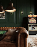 Rustic game room showcasing a blend of vintage and modern elements, with deep forest green walls, a classic leather chesterfield sofa, a vintage arcade machine, and industrial pendant lights illuminating a sleek poker table. — close-up of textures and materials