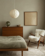 A Japandi bedroom blending vintage and modern, featuring a low oak bed, a mid-century modern teak dresser, a modern rice paper pendant light, and a vintage spindle-back chair with a sheepskin throw, all in muted tones of soft grey, beige, and sage green. — close-up of textures and materials