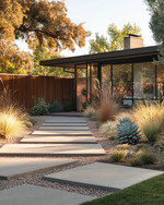 A Mid-Century Modern front yard featuring large rectangular concrete pavers, an array of sculptural succulents and ornamental grasses, and a low redwood privacy screen, all bathed in warm afternoon light. — close-up of textures and materials