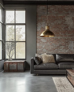 An industrial living room with a cohesive color story featuring a charcoal leather sofa, exposed brick wall, and a large metal-framed window. Warm grey walls, a polished concrete floor, and an aged brass pendant light add to the calm, urban aesthetic. — close-up of textures and materials