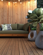 A budget-friendly Mid-Century Modern deck featuring stained pine decking, a low-slung sofa with olive green cushions, and a kidney-shaped side table. Fiberglass planters hold architectural succulents and a large fiddle-leaf fig, all under string lights with exposed bulbs. — styling and décor detail