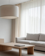 A Japandi family room showcasing a large, linen-shaded drum pendant light, a low-profile light grey sofa, and a minimalist oak coffee table, with soft daylight filtering through sheer curtains. — close-up of textures and materials