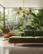 A Mid-Century Modern living room showcasing a low-slung olive green sofa with a walnut frame, an Eames Lounge Chair, and a brass Sputnik chandelier, all overlooking a lush garden through large windows. — styling and décor detail