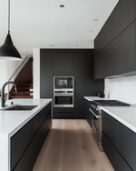 A sleek modern kitchen featuring matte black handleless cabinetry, white quartz countertops, integrated stainless steel appliances, and a minimalist black pendant light over a large kitchen island. — close-up of textures and materials