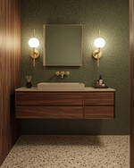 A Mid-Century Modern powder room featuring a floating walnut vanity, a small-chip terrazzo floor, and a muted olive green textured wallpaper, illuminated by brass and frosted glass sconces. — close-up of textures and materials